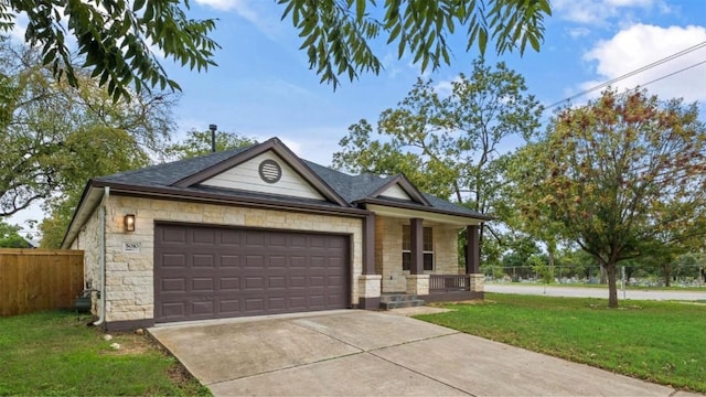 single story home with fence, concrete driveway, a front yard, stone siding, and an attached garage