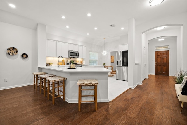 kitchen featuring white cabinetry, a peninsula, arched walkways, and appliances with stainless steel finishes