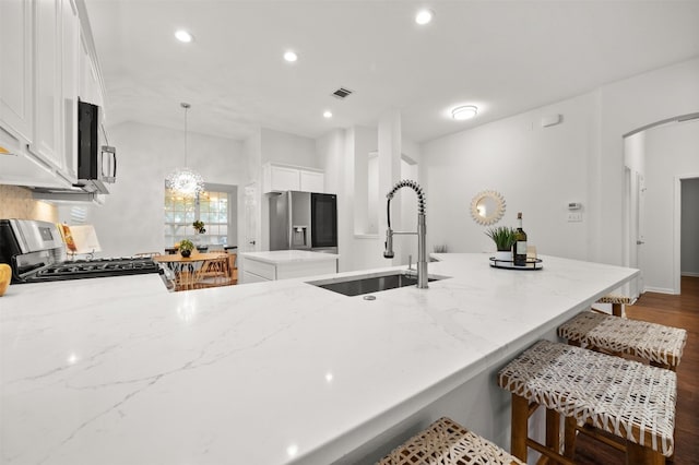 kitchen with visible vents, a sink, a kitchen island, appliances with stainless steel finishes, and a peninsula