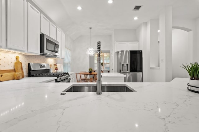 kitchen with a sink, visible vents, light stone countertops, and appliances with stainless steel finishes