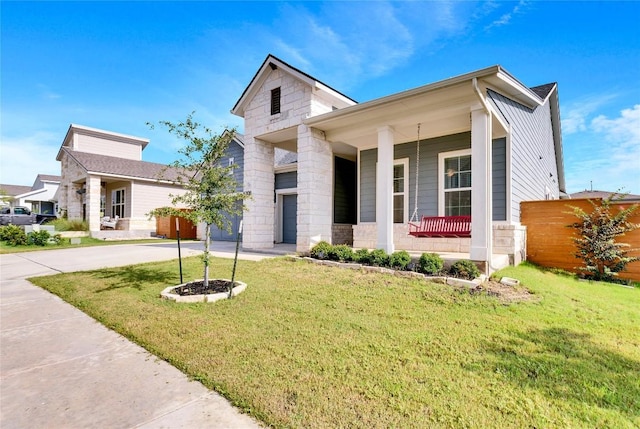 view of front of property featuring stone siding, a front lawn, covered porch, and driveway