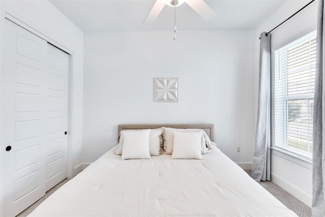 bedroom featuring multiple windows, a ceiling fan, baseboards, and carpet floors