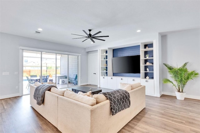 living room with built in features, visible vents, baseboards, and light wood-style floors