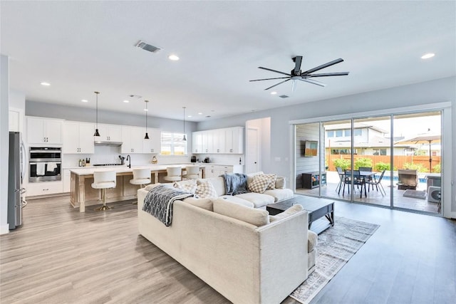 living room featuring light wood finished floors, visible vents, recessed lighting, and ceiling fan