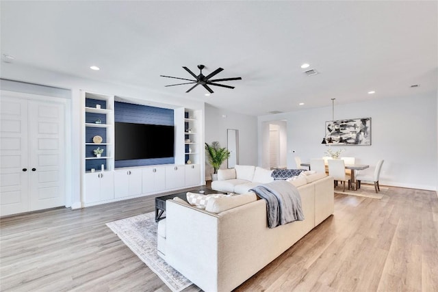 living room featuring recessed lighting, light wood-style floors, and built in shelves