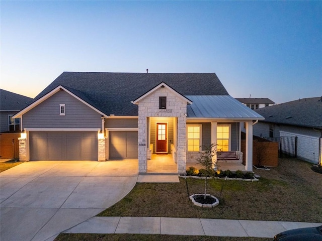 view of front of property with fence, covered porch, metal roof, driveway, and an attached garage