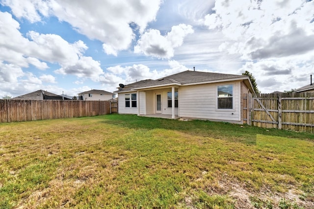 rear view of house with a yard and a fenced backyard