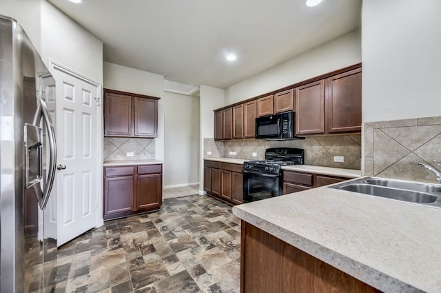 kitchen with tasteful backsplash, stone finish flooring, light countertops, black appliances, and a sink