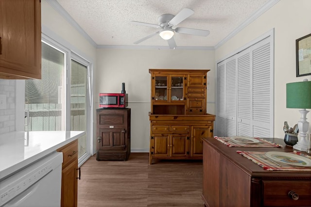 kitchen with dishwasher, crown molding, dark wood finished floors, and a textured ceiling