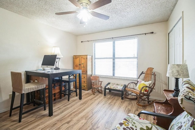 office area with baseboards, a textured ceiling, light wood-style floors, and a ceiling fan