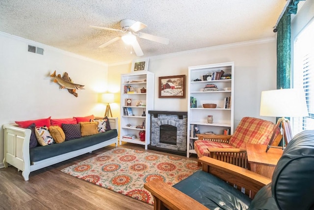 living room featuring visible vents, ornamental molding, wood finished floors, plenty of natural light, and a textured ceiling