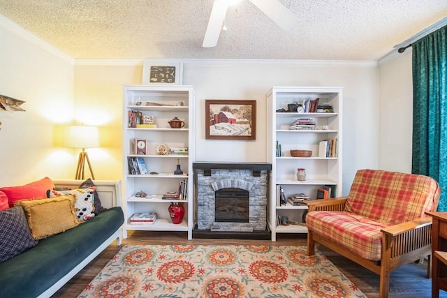 living room featuring wood finished floors, a textured ceiling, a fireplace, and crown molding