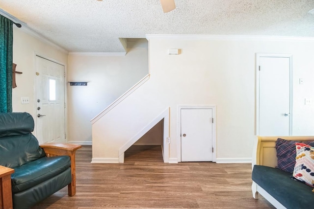 sitting room featuring baseboards, wood finished floors, a textured ceiling, and ornamental molding