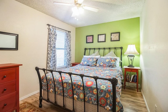 bedroom with baseboards, a textured ceiling, wood finished floors, and a ceiling fan