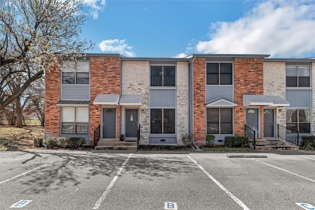 townhome / multi-family property featuring crawl space, brick siding, and uncovered parking