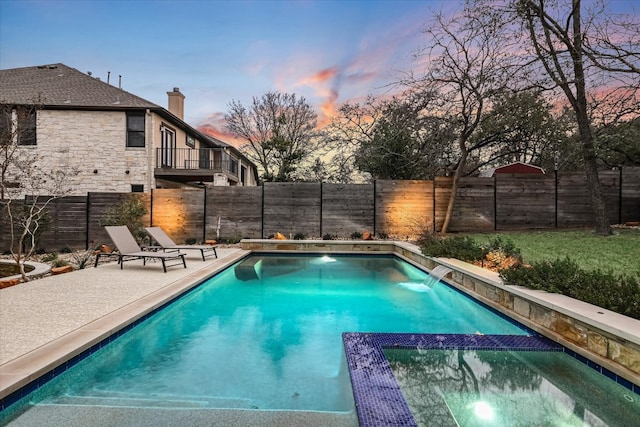 pool at dusk with a patio, a fenced backyard, and a pool with connected hot tub