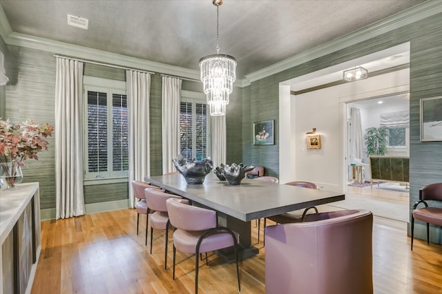 dining room featuring visible vents, light wood-style flooring, ornamental molding, an inviting chandelier, and baseboards