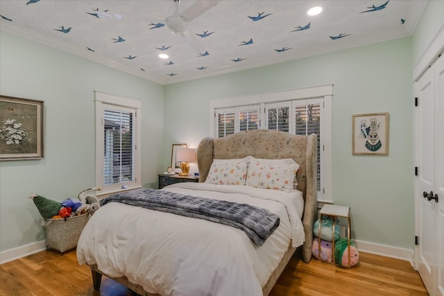 bedroom featuring wood finished floors, recessed lighting, a closet, crown molding, and baseboards