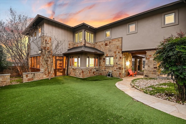 back of property featuring a patio, a lawn, stone siding, and stucco siding