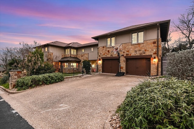 view of front of house with fence, stucco siding, driveway, stone siding, and an attached garage