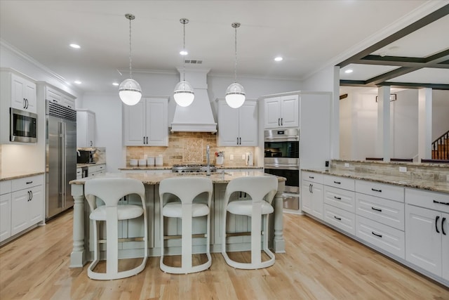 kitchen with white cabinetry, a kitchen breakfast bar, visible vents, and built in appliances