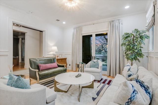 living room featuring visible vents, ornamental molding, recessed lighting, light wood-style floors, and a decorative wall