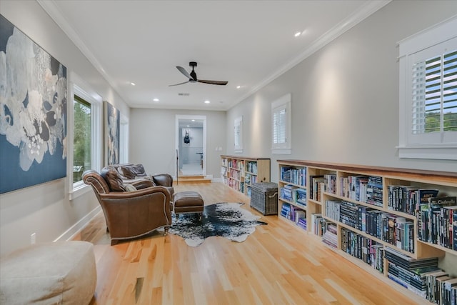 living area with a healthy amount of sunlight, crown molding, baseboards, and wood finished floors