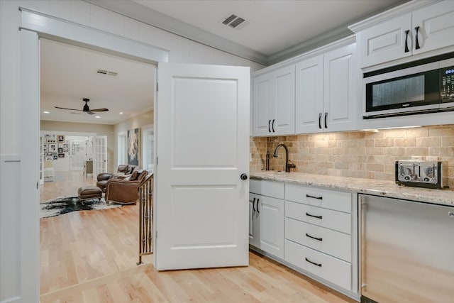 kitchen with visible vents, light wood-style flooring, built in microwave, white cabinetry, and fridge