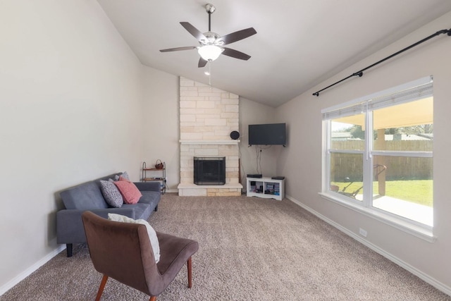 living area featuring carpet floors, a stone fireplace, baseboards, ceiling fan, and vaulted ceiling