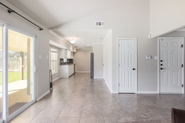 interior space featuring light tile patterned flooring, baseboards, visible vents, and high vaulted ceiling