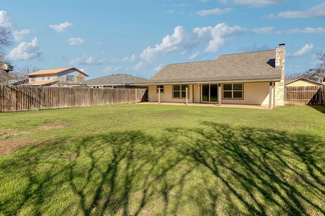 back of house featuring a patio, a lawn, a fenced backyard, and a chimney