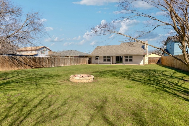 back of property with a yard, a fire pit, and a fenced backyard