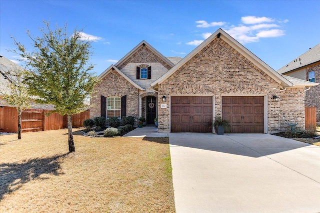 french country inspired facade featuring concrete driveway, a garage, fence, and brick siding