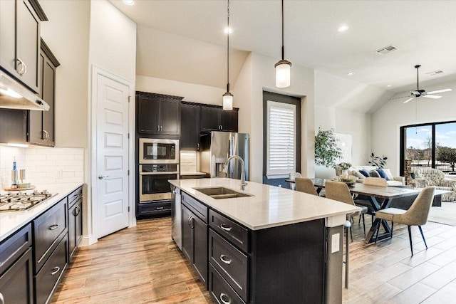 kitchen with visible vents, a sink, open floor plan, appliances with stainless steel finishes, and lofted ceiling