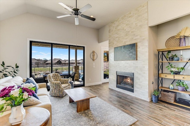 living room with a ceiling fan, wood finished floors, baseboards, high vaulted ceiling, and a fireplace