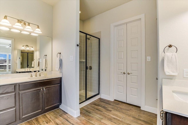 full bath featuring a stall shower, a closet, wood finished floors, and vanity