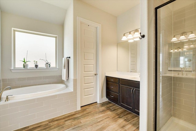 bathroom with vanity, a bath, wood finished floors, and a stall shower