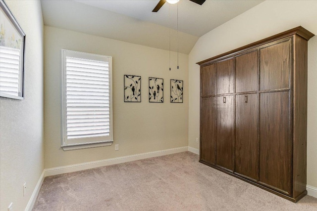 unfurnished bedroom with ceiling fan, baseboards, lofted ceiling, and carpet