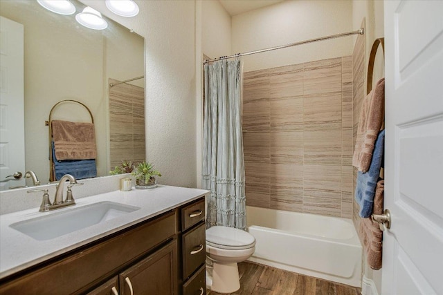 bathroom featuring toilet, shower / tub combo with curtain, wood finished floors, a textured wall, and vanity