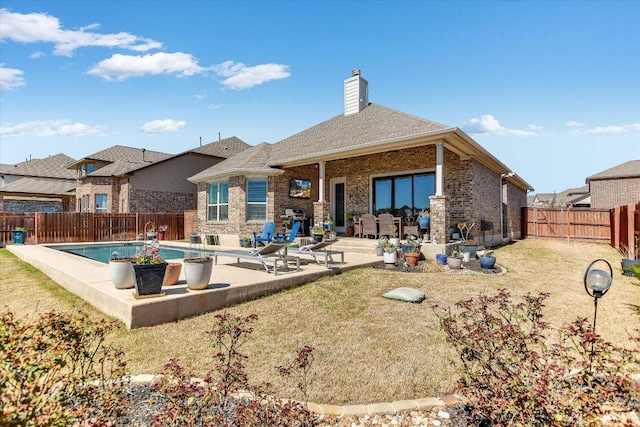 back of house featuring brick siding, a fenced in pool, a chimney, a fenced backyard, and a patio area