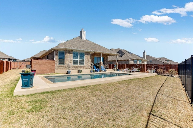 rear view of property with a fenced in pool, brick siding, a fenced backyard, and a patio area