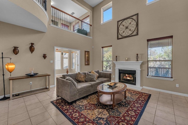 tiled living room featuring baseboards and a warm lit fireplace