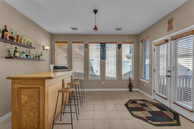 interior space with visible vents, a dry bar, and baseboards