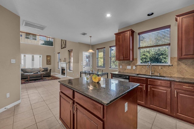 kitchen with visible vents, a warm lit fireplace, a sink, tasteful backsplash, and open floor plan