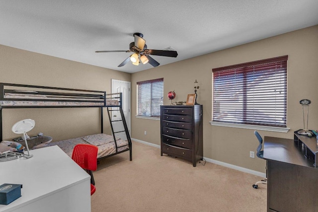 bedroom with a textured ceiling, light colored carpet, baseboards, and ceiling fan