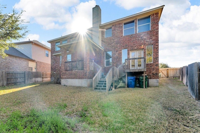 back of house featuring a yard, brick siding, a fenced backyard, and a chimney