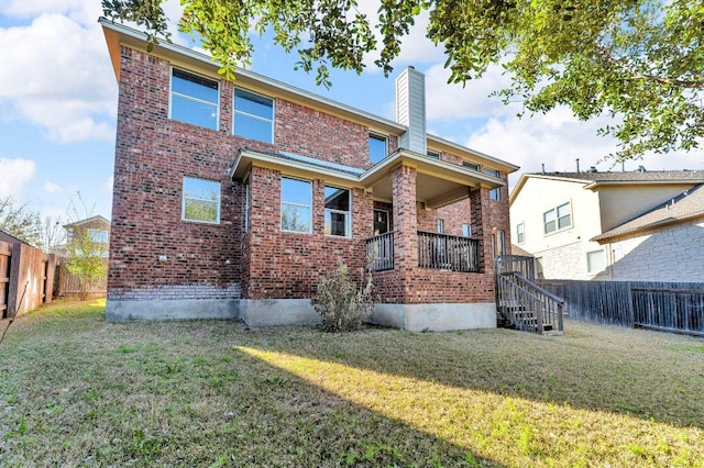 back of house featuring brick siding, a fenced backyard, a chimney, and a yard