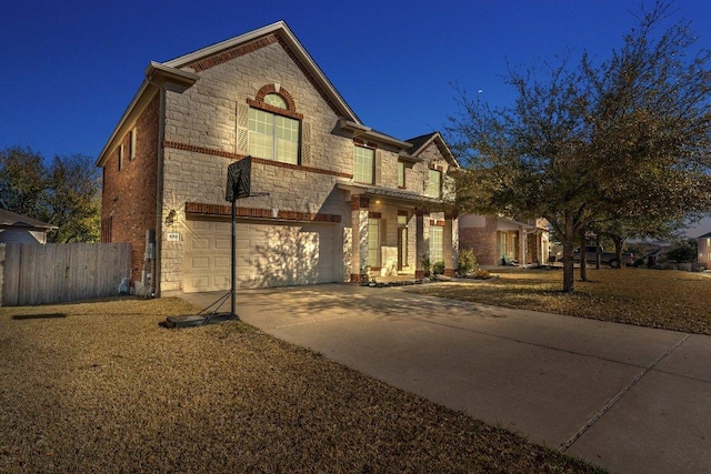 view of front of house featuring a garage, stone siding, concrete driveway, and fence