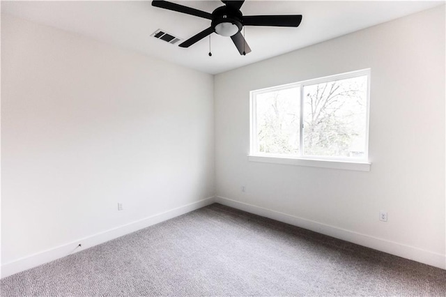 carpeted spare room with visible vents, a ceiling fan, and baseboards