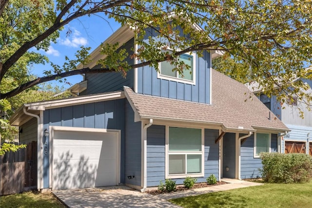 view of front of home with board and batten siding, a shingled roof, a front lawn, driveway, and an attached garage